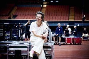 harry styles seated wearing white loafers