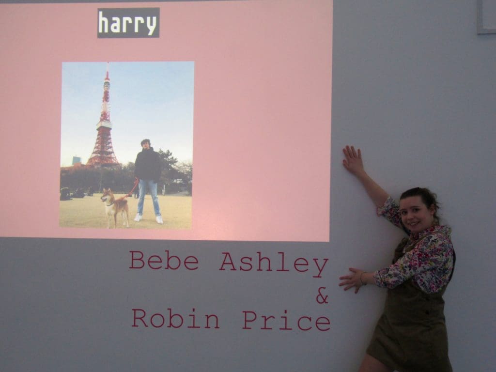 Bebe Ashley standing next to a digital arts exhibition with 'harry' scrolling across the screen