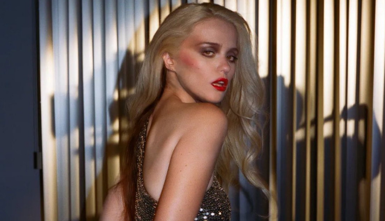 Sky Ferreira is wearing a silver sparkly dress, a bright red lip, and looking over her shoulder.
