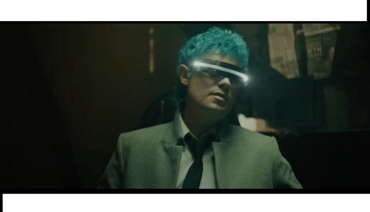 Nick Wold in body language music video, wearing futurisitc glasses, black tie & gray jacket