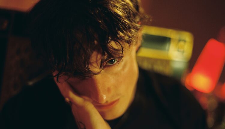 An up-close image of Thomas placing his hand on his cheek for the 'beg' music video.